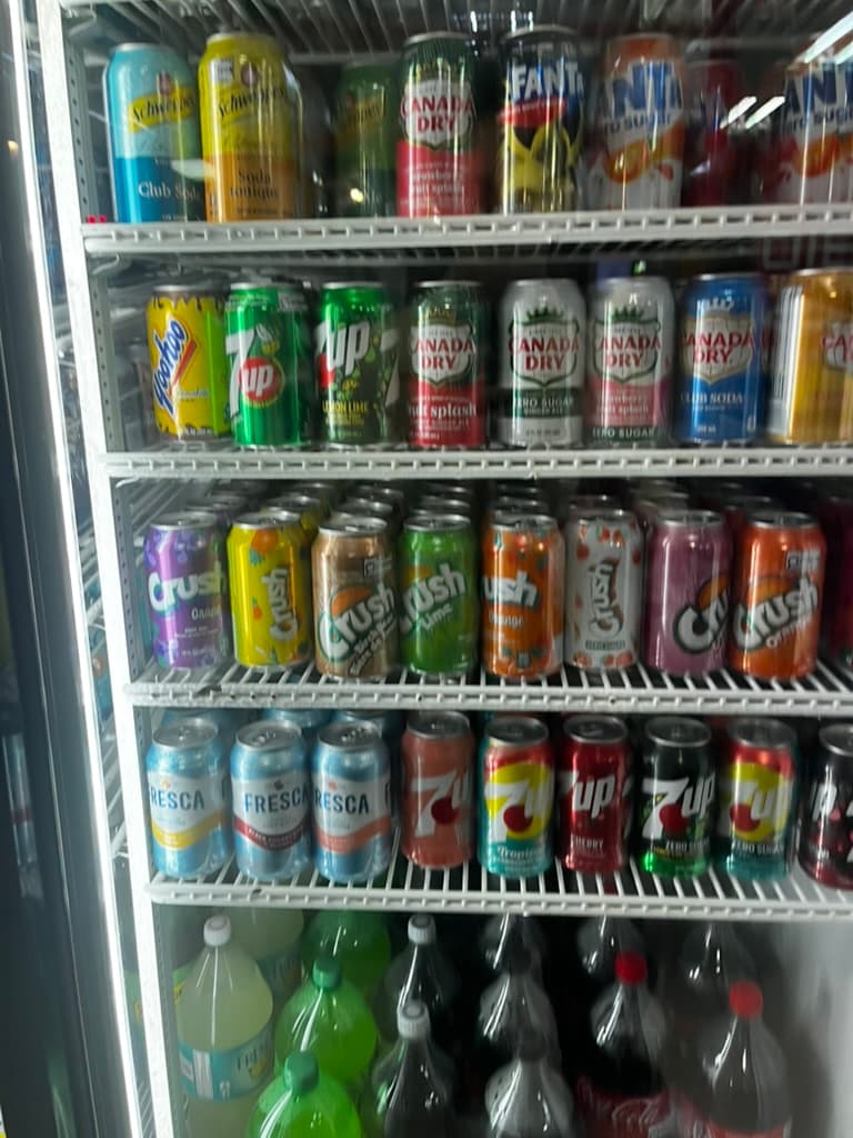 Convenience-store fridge filled with colorful soda cans arranged in rows